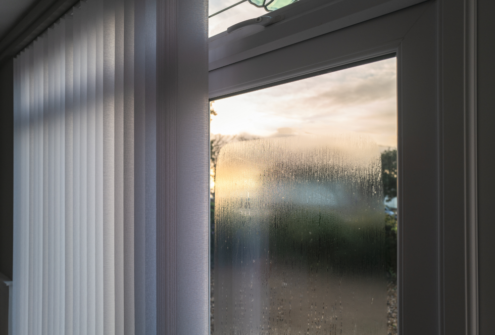 window with condensation and the sun setting in distance