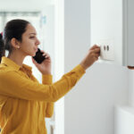 woman on the phone while adjusting her boiler