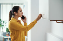woman on the phone while adjusting her boiler