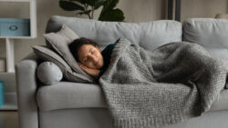 woman sleeping on a couch under a blanket