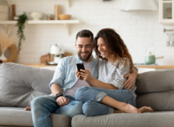 a man and woman look at their phone on the couch after having maintenance done on their air handler in Fort Wayne, IN