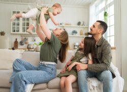 a mother and father play with their two kids on their couch in their Auburn, IN home while waiting for boiler maintenance services